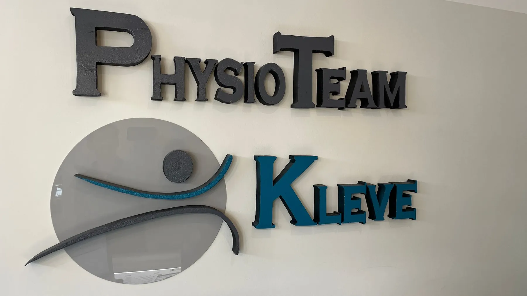 PhysioTeam-Kleve-Logo an der Wand im Empfang